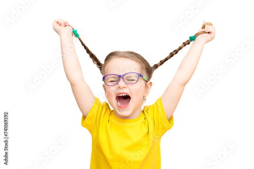 A funny girl in glasses and a yellow T-shirt holds pigtails in her hands. White background