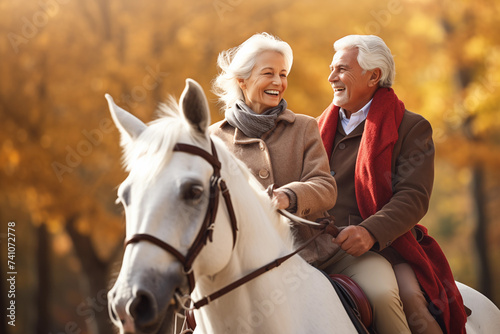 Senior couple with white horse in autumn park. They are looking at camera and smiling