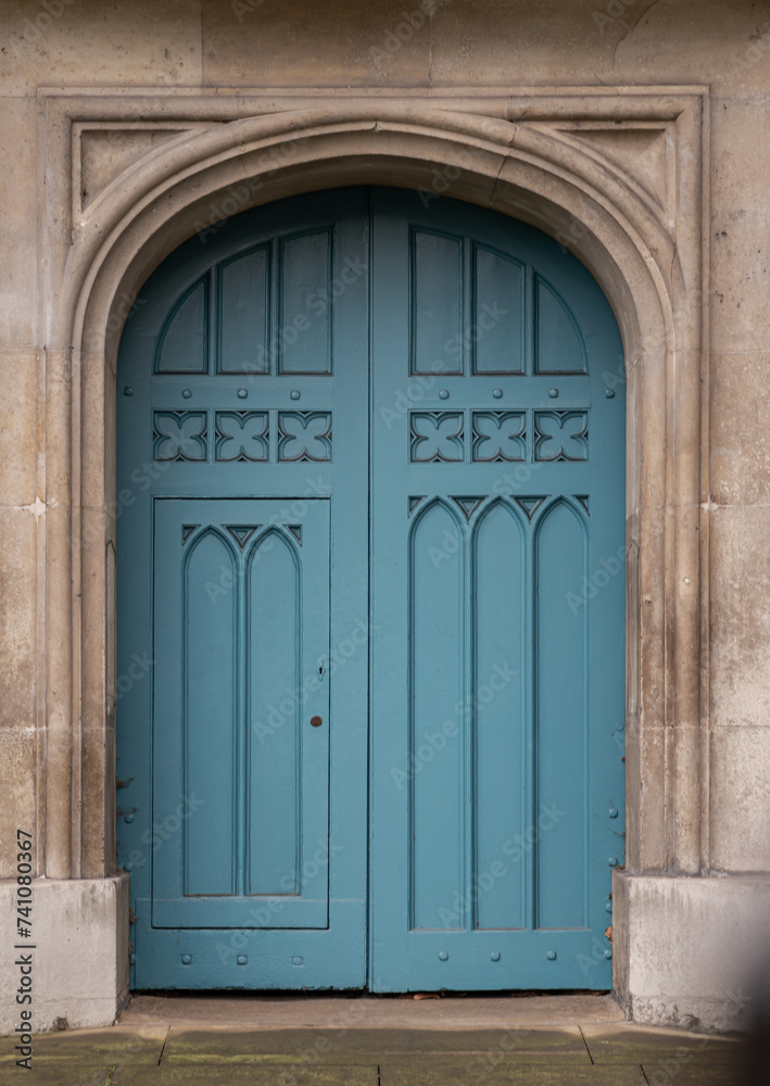 Details of Closed blue wooden church doorway in a gothic stone wall at City of Westminster, Arched medieval door in European style, Space for text, Selective focus. Details of Closed blue wooden church doorway in a gothic stone wall at City of Westminster, Arched medieval door in European style, Space for text, Selective focus.