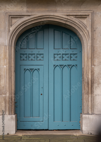 Details of Closed blue wooden church doorway in a gothic stone wall at City of Westminster, Arched medieval door in European style, Space for text, Selective focus.