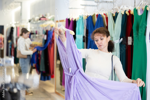 Adult woman buying long dress in clothing store