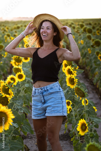 Obraz na płótnie Young smiling woman in a sunflower plantation during golden hour w salonie