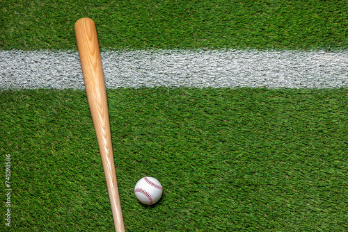 Baseball and wooden bat on grass field with white stripe overhead view