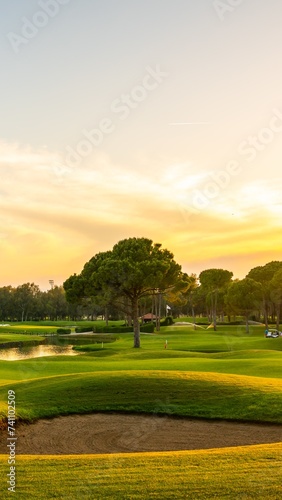 Panorama of the most beautiful sunset or sunrise. Sand bunker on a golf course without people with a row of trees in the background