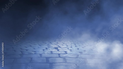 Smoke Blowing Across Cobblestones 4K Loop features billows of blue tinted smoke or fog rolling across a cobblestone pavement that recedes into the darkness. photo