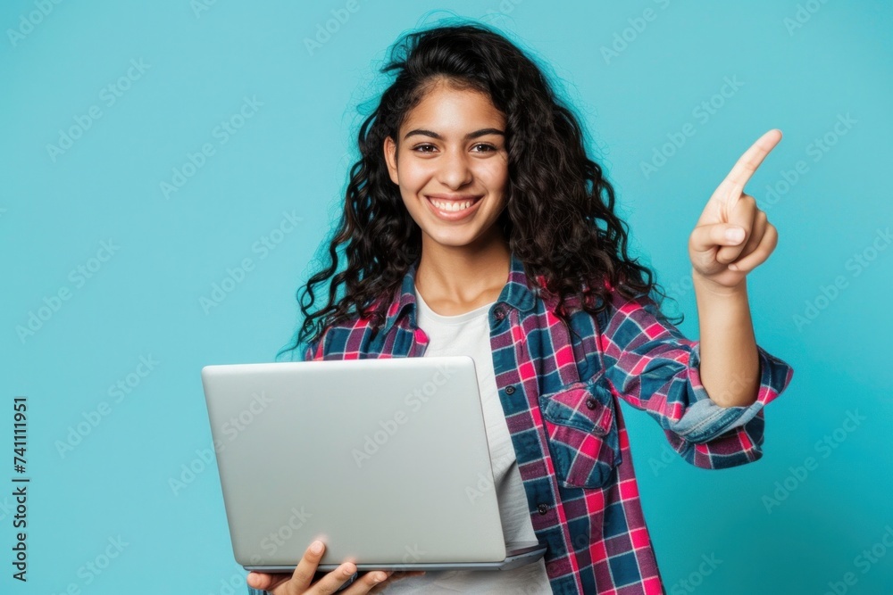 Happy young woman pointing at laptop isolated on blue background Holding a computer to present an advertisement Happy young woman pointing at laptop isolated on blue background Holding a computer to present an advertisement
