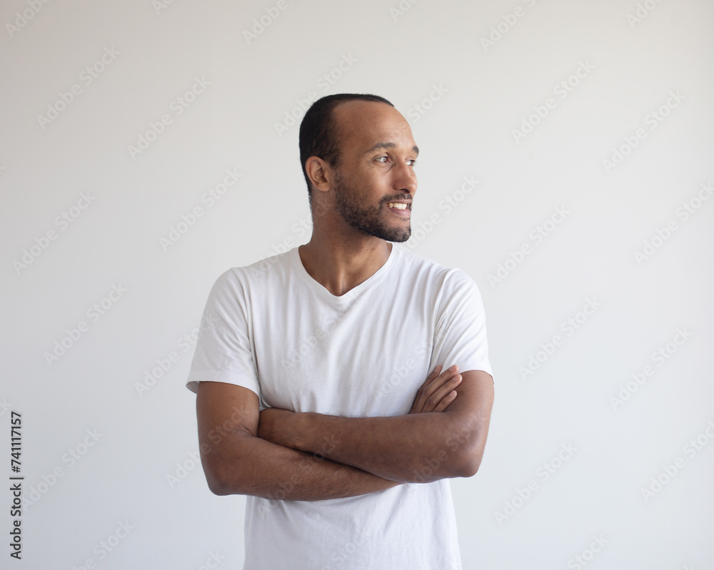 Portrait of young afro american man standing with arms crossed against light grey background Portrait of young afro american man standing with arms crossed against light grey background