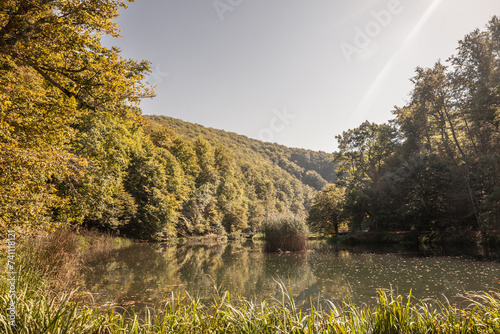 Fototapeta Naklejka Na Ścianę i Meble -  Panorama of the pond Jankovac, a small water lake surrounded by trees and forest in the Papuk mountain, a major national park of Croatia, in the Slavonia region.