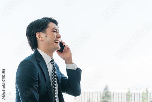 オフィスでスマホを使う若いアジア人ビジネスマン（電話・営業・アポ・営業活動）
