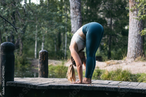 woman in sportswear doing yoga in nature near a lake
