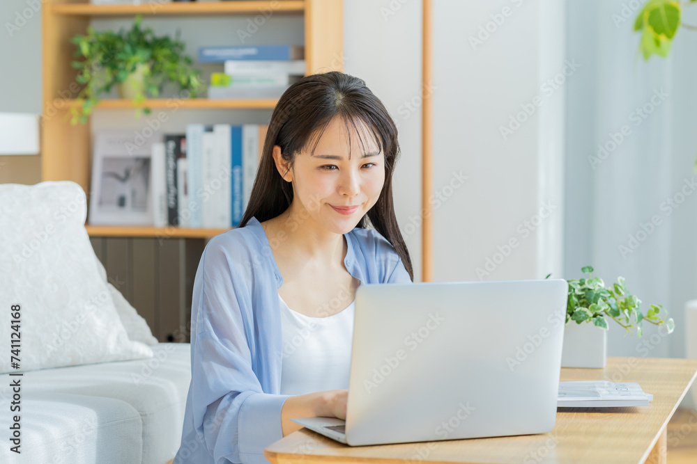 自宅でノートパソコンを操作する若い女性 自宅でノートパソコンを操作する若い女性