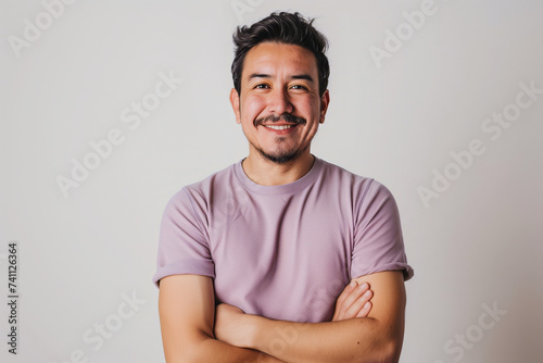Confident and Smiling Man with Mustache in Purple T-Shirt Poses with Arms Crossed on a Plain Background