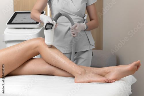 Beautician makes laser hair removal on woman's legs