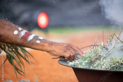 Human hand with green branch of eucalyptus, smoke and fire, the smoke ritual rite at a indigenous community event in Australia