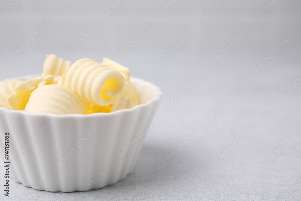 Tasty butter curls in bowl on light grey table, closeup. Space for text Tasty butter curls in bowl on light grey table, closeup. Space for text