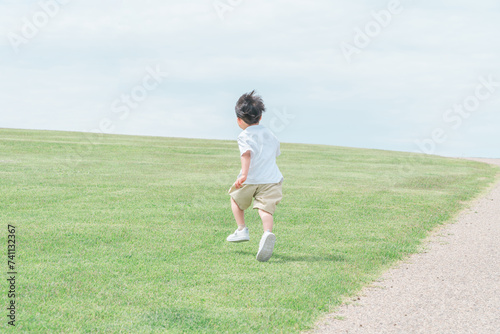 芝生の丘・公園を走る活発な子供・男の子 