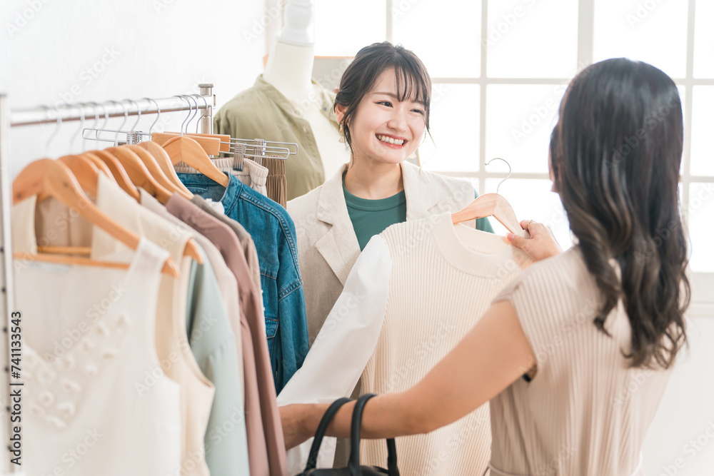 Obraz premium アパレルショップで洋服を買い物・ショッピングする女性とショップ店員 