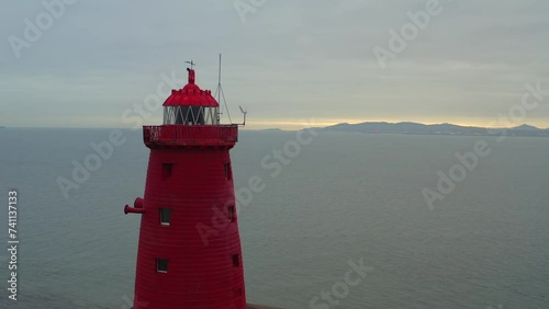 Drone orbiting Poolbeg lighthouse. Red light flickering against sunrise photo