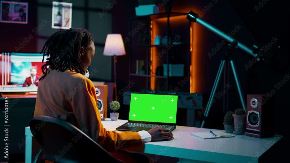 African american young woman looks at laptop with greenscreen, sitting ...