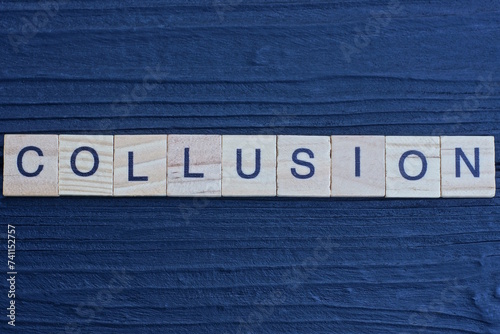 text the word collusion from brown wooden small letters on a black table