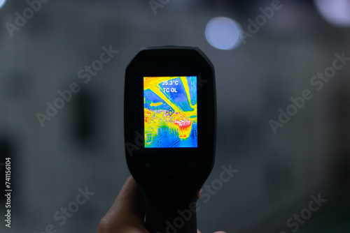 Professional Electrician use thermal infrared camera or thermometer scanning electrical system for preventive maintenance,Industrial thermography,Thermal image of power electric. photo