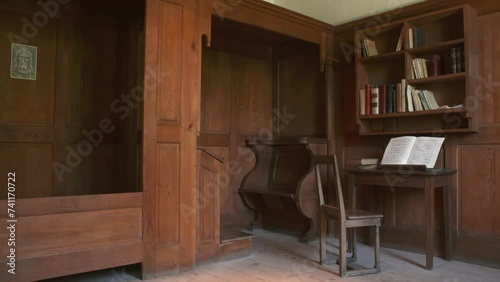Open Christian Hymns book on a wooden table under bookshelves with old wooden furniture in a room photo