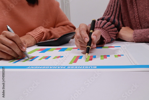 A woman sits at a desk, close up, discussing business. A chart lies on the desk, aiding in the discussion and decision-making process.