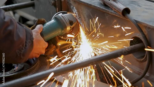 Close-up of a worker grinding metal with sparks flying, in natural light photo