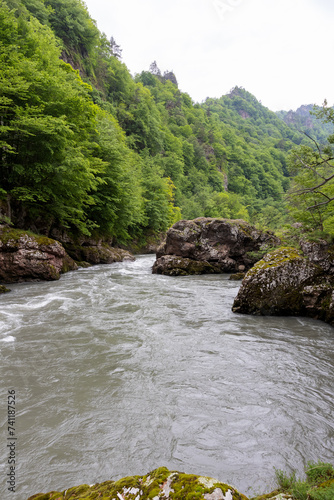 A full-flowing river, a mountainous area, a cloudy day, summer walks in the bosom of nature, a panorama of the area.