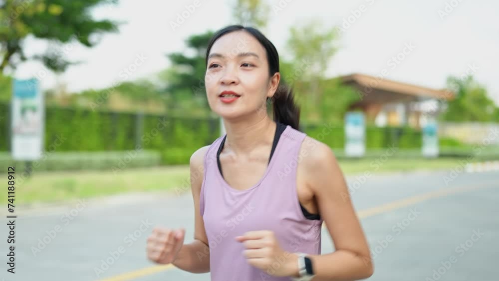 Female jogger, a young Asian woman wearing pink sportswear As she runs in the park in the morning sun. Soft sunlight. Health and outdoor activity concept. Female jogger, a young Asian woman wearing pink sportswear As she runs in the park in the morning sun. Soft sunlight. Health and outdoor activity concept.