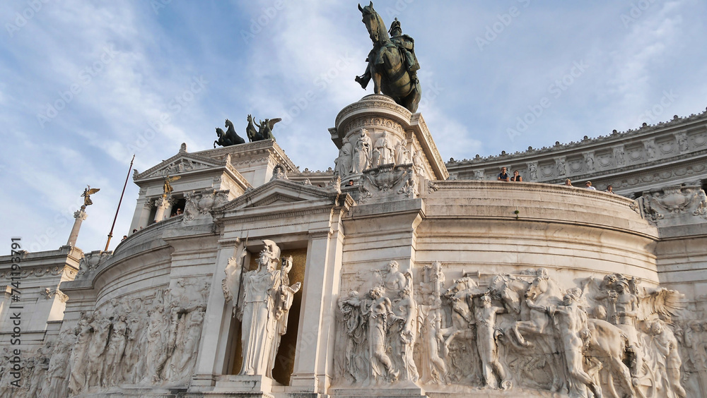 Majestic monument with equestrian statue, adorned with sculptures and bas-reliefs, under a clear blue sky.