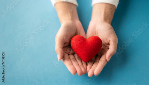 holding red heart symbol on blue backdrop  conveying love  care  and compassion