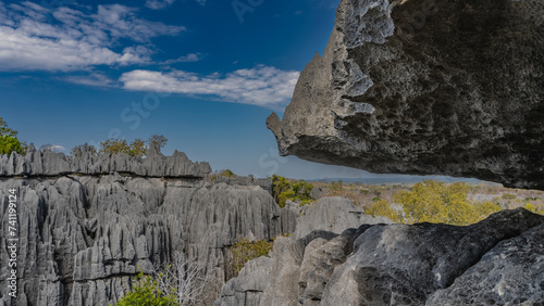 The incredible landscape of Madagascar. Grey limestone karst rocks with steep furrowed slopes against a blue sky background. A large fragment of cliff in the foreground.  Close-up. Tsingy De Bemaraha photo