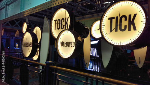 Illuminated vintage clocks in a dark setting with words "TOCK TICK" creating a conceptual timepiece display.