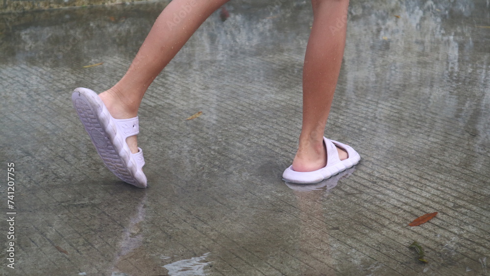 children's feet wearing slippers stepping on puddles of water