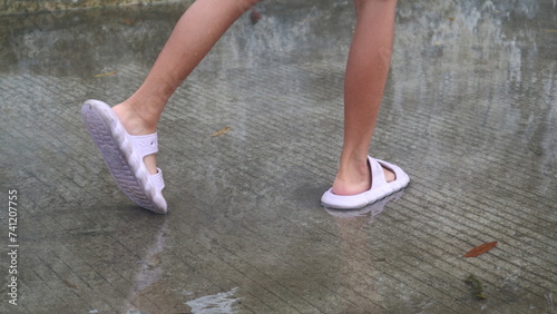 children's feet wearing slippers stepping on puddles of water © Wahjoekris