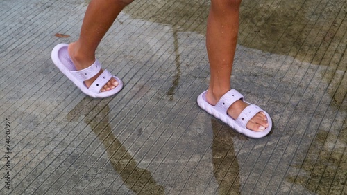 children s feet wearing slippers stepping on puddles of water