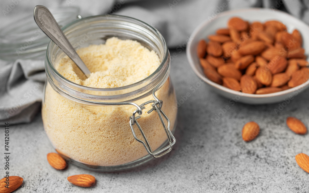 Fresh almond flour in a glass jar and almonds Fresh almond flour in a glass jar and almonds