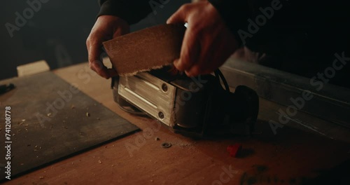 Removing an old, damaged sanding belt from an electric belt grinder. photo