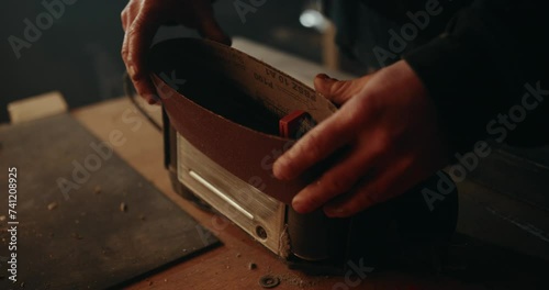 Putting a paper sanding belt on an electric belt grinder. Slow motion close up shot photo