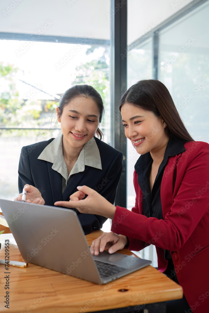 Two businesswomen discussing project strategy in office conference room Businesswoman discusses project planning with colleagues in modern workplace, gives advice on financial data report Two businesswomen discussing project strategy in office conference room Businesswoman discusses project planning with colleagues in modern workplace, gives advice on financial data report