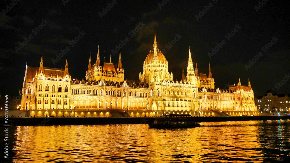 The Hungarian Parliament Building at night, brilliantly lit against the dark sky, reflected in the waters of the Danube River.