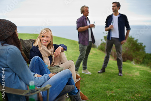 Friends, men and women with drinks for relax on grass in nature with happiness for holiday and vacation. People, smile and alcohol in countryside or lake for adventure, travel and bonding in forest