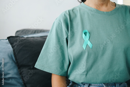 Close up Teal Awareness Ribbon on Teal T-Shirt to Support Cervical Cancer Survivor. Ovarian Cancer Month.  photo