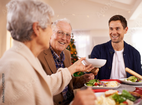 Senior, father and happy with family at Christmas dinner with food and reunion celebration in home. Holiday, event and man smile with lunch, roast dish and relax at dining room table with elderly