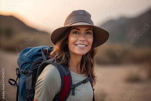 Portrait of a happy hiker woman in the desert at sunset
