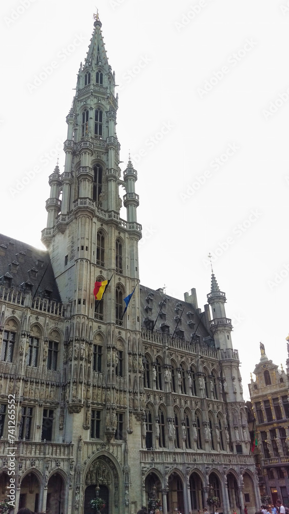 The Town Hall of Brussels with its detailed facade and tower adorned with flags.