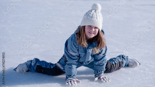 happy girl, child sitting on ice in winter in skates smiling 9:16. High quality photo