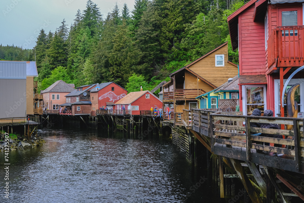 Historic old wooden houses facades along Creek in downtown Ketchikan, Alaska with colorful buildings, fisherman homes, marina with boats and tourist traffic on road popular cruise ship destination