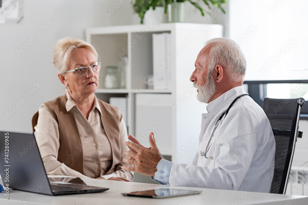 A specialist doctor consults with an elderly female patient in his office A specialist doctor consults with an elderly female patient in his office
